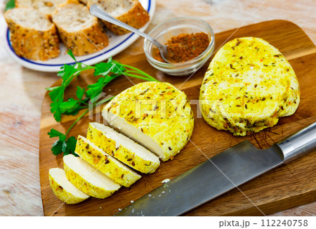 Slices of spicy roasted cottage cheese with turmeric and cumin on wooden board 112240758