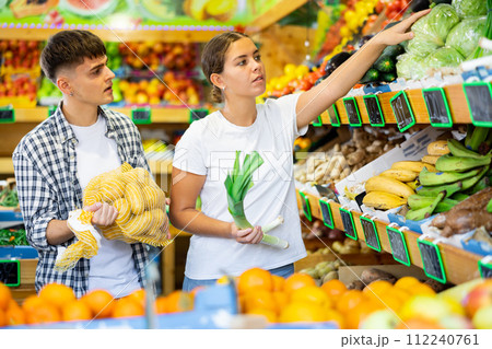 Young husband and wife choose fresh vegetables together in grocery supermarket 112240761