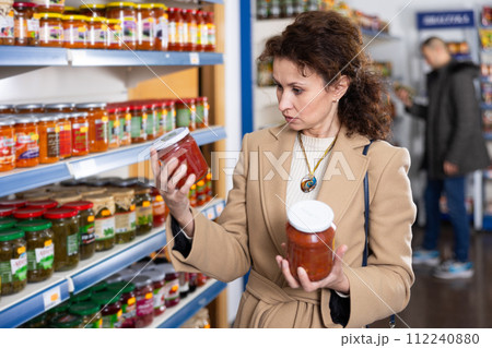 Adult woman chooses lecho in store 112240880