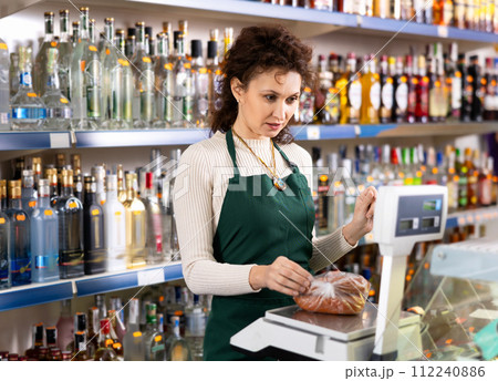 Woman works as salesperson in alcohol department of Russian store. 112240886