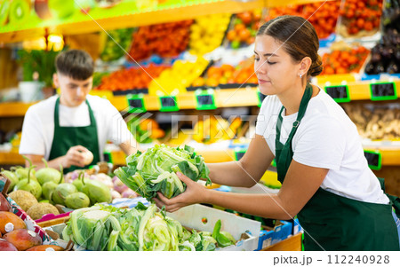 Hardworking young saleswoman puts cabbage on the counter Hardworking young saleswoman puts cabbage on the counter 112240928