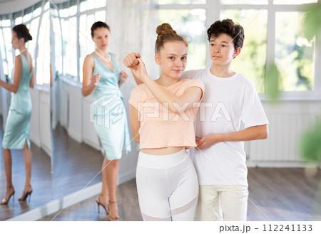 Adolescent dance duo, boy and girl, refining slow foxtrot with female coach Adolescent dance duo, boy and girl, refining slow foxtrot with female coach 112241133