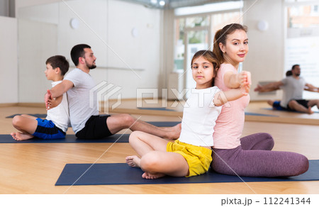 Children and parents sitting back to back on yoga mats 112241344