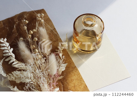 茶色の蝋引き紙の上に置かれた白を基調としたドライフラワーと茶色の小さな花瓶 112244460