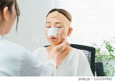美容外科で整形手術を受けて術後に医師から診察を受ける女性 美容外科で整形手術を受けて術後に医師から診察を受ける女性 112244462