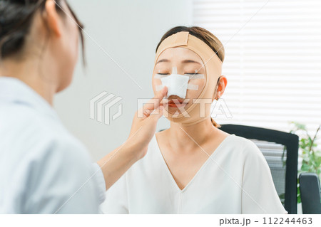 美容外科で整形手術を受けて術後に診察を受ける女性（鼻整形・隆鼻術・プロテーゼ） 112244463