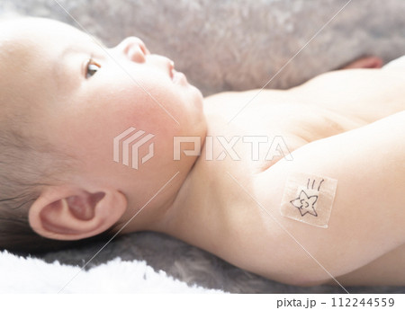 右腕に注射跡の絆創膏を貼っている生後半年のハーフの男の子赤ちゃん 112244559