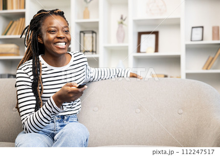 Afro American Woman Enjoying Leisure Time with Remote at Home 112247517