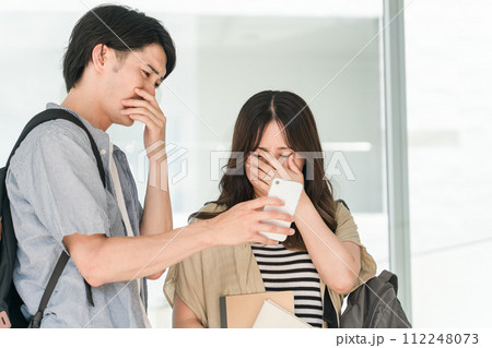 スマホを見てショックを受ける学生・大学生の男女（悲しい・訃報・悲報・不合格） 112248073