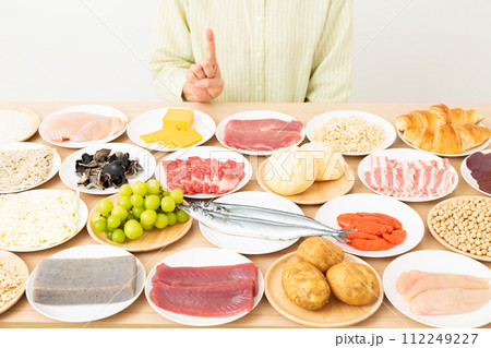 色々な食材と人差し指を立てるミドル女性 112249227
