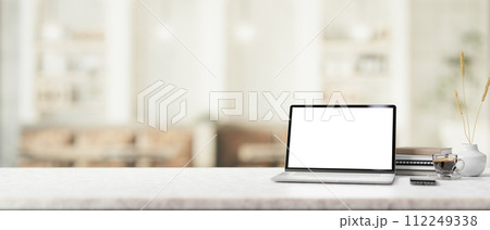 A white marble table features a white-screen laptop mockup in a contemporary, cosy coffee shop. 112249338
