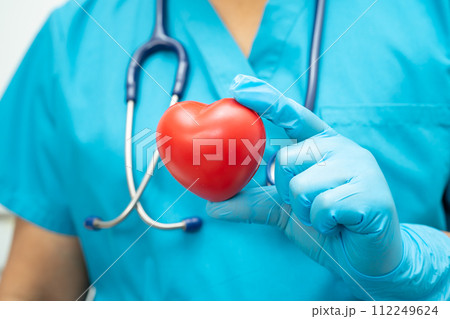 Doctor holding a red heart in hospital ward, healthy strong medical concept. Doctor holding a red heart in hospital ward, healthy strong medical concept. 112249624
