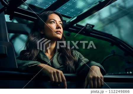 Young businesswoman driving a car with solar panel on the background. Young businesswoman driving a car with solar panel on the background. 112249866