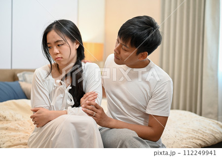 A man apologizes, asking for forgiveness from his sad girlfriend after their argument in the bedroom 112249941