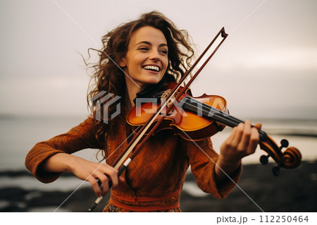 Joyful violinist playing by the sea at sunset 112250464