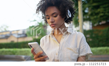 Beautiful woman listening to music in headphones, using app on smartphone 112251723