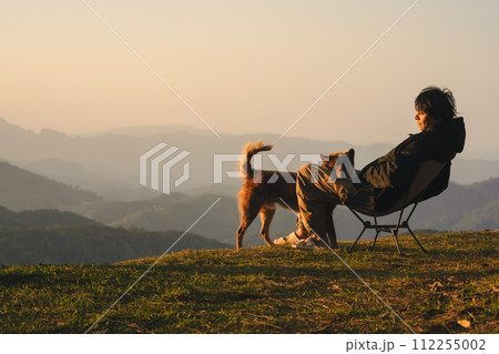 nature traveling with solo man play with dog and see sunrise with layer of mountain 112255002