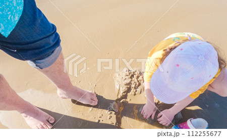 A little girl joyfully clamming on Pismo Beach, bundled up for the winter chill as she explores the sands for seashells and clams. 112255677