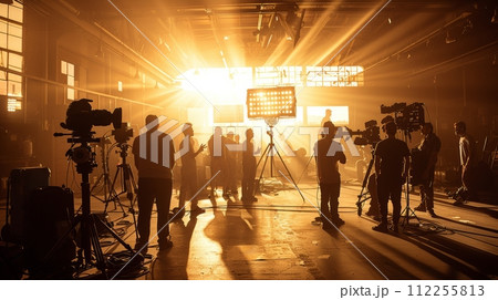 AI-generated content. Warm light on film set bathed, creating silhouette effect. Indoor space with natural light. Crew members working with filming equipment 112255813