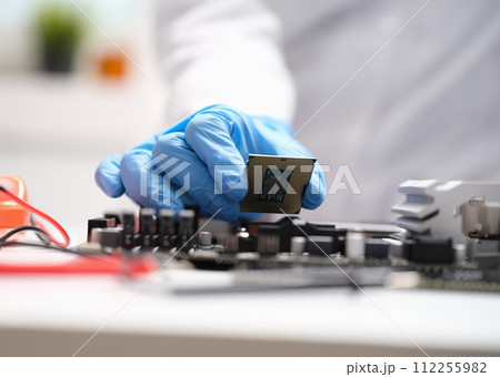 Technician connects a CPU microprocessor to motherboard socket 112255982