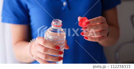 Woman opening plastic bottle with clean water. 112256315