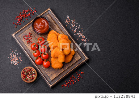 Delicious fresh crispy chicken nuggets on a dark concrete background Delicious fresh crispy chicken nuggets on a dark concrete background 112258943