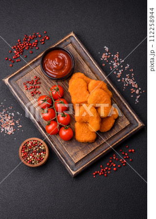 Delicious fresh crispy chicken nuggets on a dark concrete background Delicious fresh crispy chicken nuggets on a dark concrete background 112258944