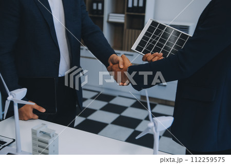Two Young Engineers Expertise in Solar Cell Installation Meetings and Discussion in The Job. Planning to Install Solar Photovoltaic Panels on Roof Top in The Office Room with Factory Building Plan. Two Young Engineers Expertise in Solar Cell Installation Meetings and Discussion in The Job. Planning to Install Solar Photovoltaic Panels on Roof Top in The Office Room with Factory Building Plan. 112259575