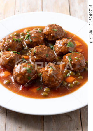 Meatballs, green peas and carrot with tomato sauce on wooden table Meatballs, green peas and carrot with tomato sauce on wooden table 112260713