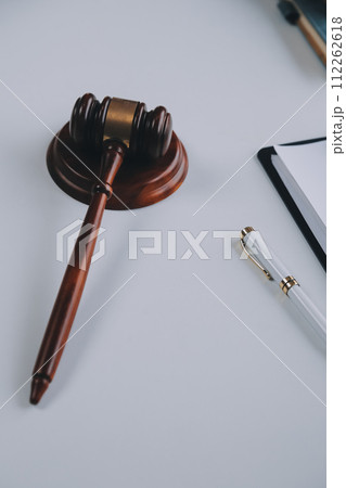 Justice and Law concept. Legal counsel presents to the client a signed contract with gavel and legal law or legal having team meeting at law firm in background Justice and Law concept. Legal counsel presents to the client a signed contract with gavel and legal law or legal having team meeting at law firm in background 112262618