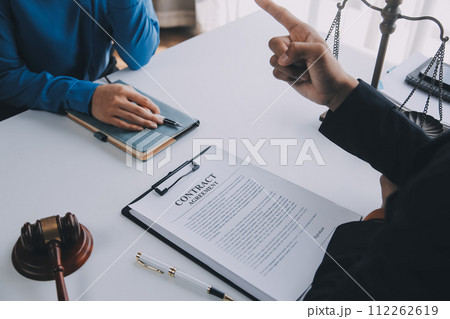 Justice and Law concept. Legal counsel presents to the client a signed contract with gavel and legal law or legal having team meeting at law firm in background Justice and Law concept. Legal counsel presents to the client a signed contract with gavel and legal law or legal having team meeting at law firm in background 112262619
