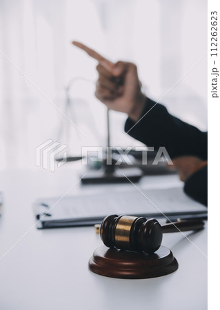 Justice and Law concept. Legal counsel presents to the client a signed contract with gavel and legal law or legal having team meeting at law firm in background 112262623