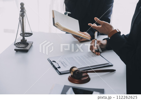 Justice and Law concept. Legal counsel presents to the client a signed contract with gavel and legal law or legal having team meeting at law firm in background Justice and Law concept. Legal counsel presents to the client a signed contract with gavel and legal law or legal having team meeting at law firm in background 112262625