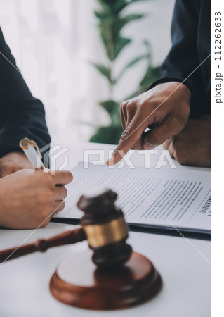 Justice and Law concept. Legal counsel presents to the client a signed contract with gavel and legal law or legal having team meeting at law firm in background 112262633