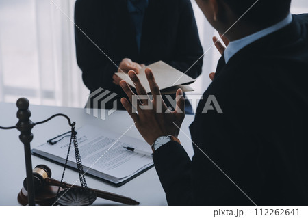 Justice and Law concept. Legal counsel presents to the client a signed contract with gavel and legal law or legal having team meeting at law firm in background 112262641