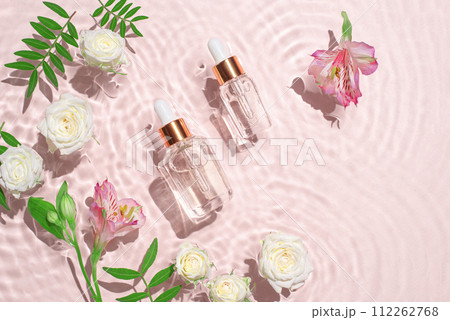 Cosmetic bottles with pipette and flowers. Cosmetic bottles with pipette and flowers. 112262768