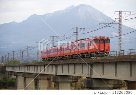 大山を背景に日野川の鉄道橋梁を通過するキハ40系キハ47形普通列車（4両編成）の後ろ姿 112263080
