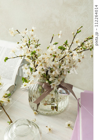 Spring twigs with flowers in a jar, with books on a light background. Spring twigs with flowers in a jar, with books on a light background. 112264014