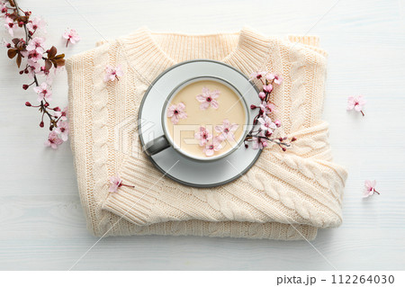 Spring twigs with flowers with a cup of hot drink, on a light wooden background. 112264030