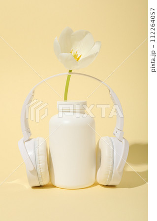 A bottle with bio-additives, with flowers, on a light background. A bottle with bio-additives, with flowers, on a light background. 112264057