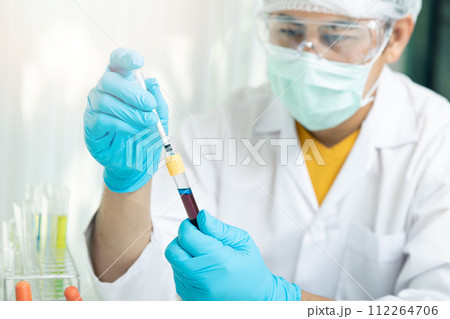 Researcher or scientists loads liquid into blood sample in test tube. Researchers are developing vaccines and medicine to treat the COVID-19 virus. 112264706