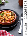 Homemade Ropa vieja, typical Canarian dish of chickpeas stew with chicken and potatoes in a earthenware casserole on marble table. Vertical format. 112265398