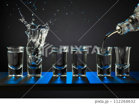 Barman pouring hard spirit into glasses. Barman pouring hard spirit into glasses. 112268632