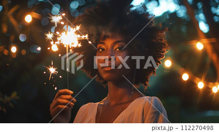 AI-generated content. Elegant young African woman in a sparkling dress celebrates with a sparkler. Portrait of a pensive woman against the backdrop of festive evening garlands. Party, graduation or 112270498