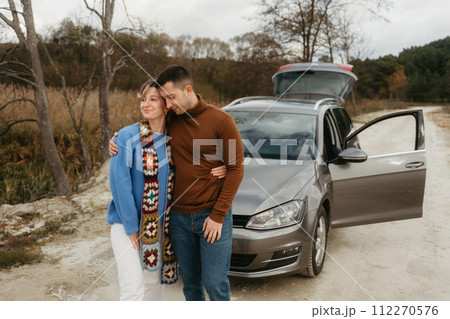 A man and woman by a car on a dirt road, adult couple on autumn roadtrip 112270576