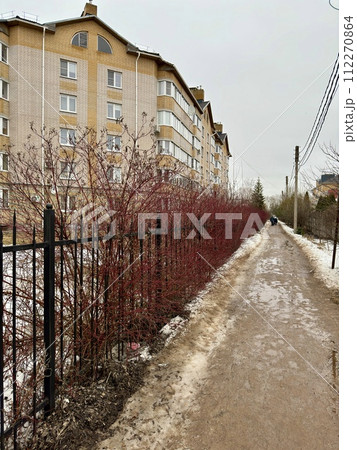 Melting dirty snow on the streets of the city during the daytime in winter. The pedestrian road along the fence has snow with sand and mud. Traces of people and pets Melting dirty snow on the streets of the city during the daytime in winter. The pedestrian road along the fence has snow with sand and mud. Traces of people and pets 112270864