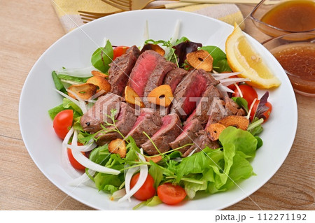 ボリューミーなステーキサラダ、野菜サラダ、牛モモ肉のステーキ、ドレッシング添え。 112271192