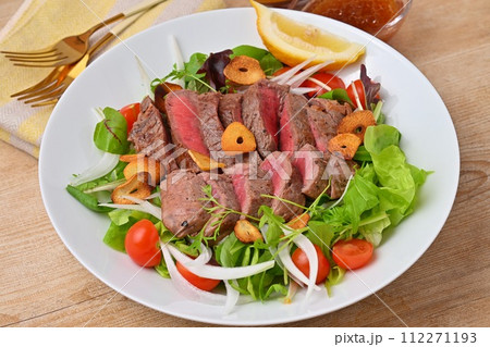 ボリューミーなステーキサラダ、野菜サラダ、牛モモ肉のステーキ、ドレッシング添え。 112271193