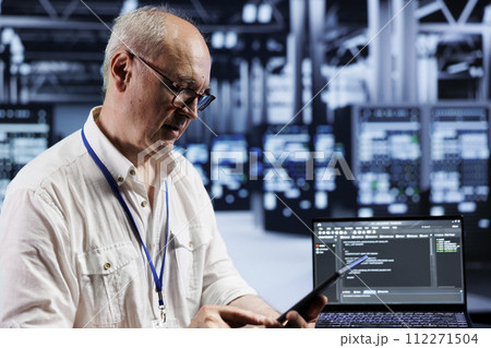 Aged precise engineer coding in technologically advanced data center using javascript language. Expert updating software on server racks on laptop terminal, ensuring errorless performance and security Aged precise engineer coding in technologically advanced data center using javascript language. Expert updating software on server racks on laptop terminal, ensuring errorless performance and security 112271504