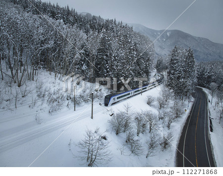 雪の佐野坂峠を疾走する特急あずさ号　長野県白馬村（ドローンによる空撮） 112271868